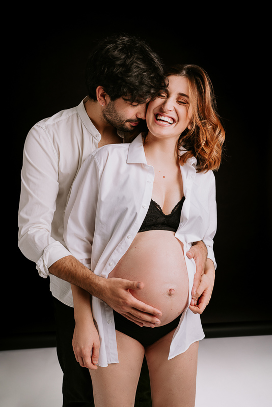 Coppia che sorride sul set fotografico per il servizio maternity