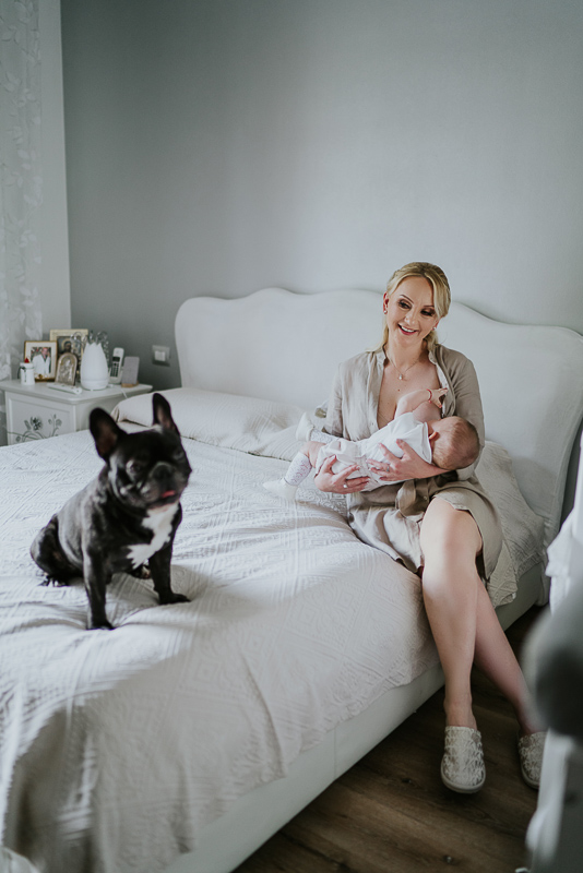 Preparazione bambino battesimo sul letto con mamma e cane